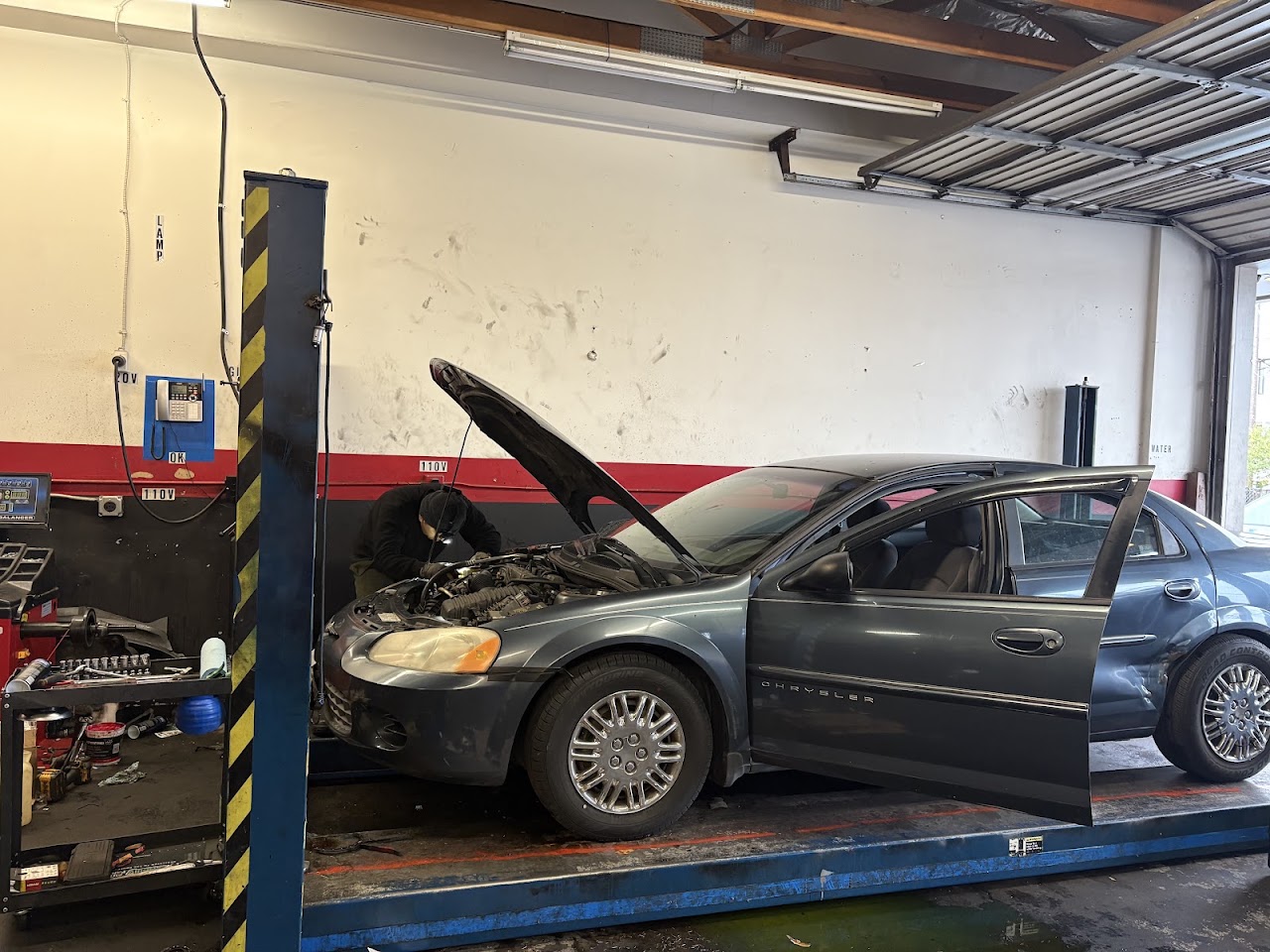Technician working under the hood of a car in the service bay